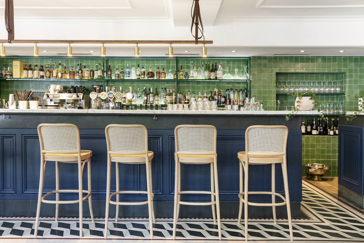 Barbereich mit schwarz weißen Terazzoplatten und grünen Zementfliesen an der Wand 