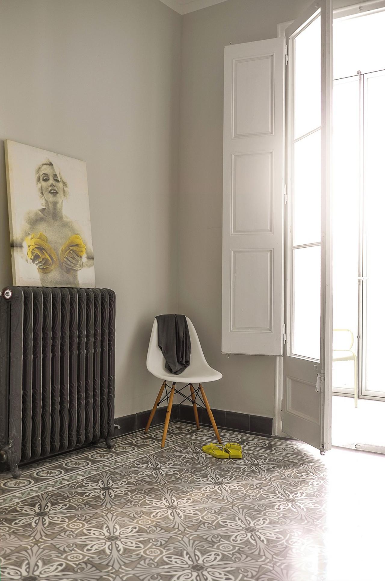 Schlafzimmer mit Marilyn Monroe Bild auf schwarzer Heizung Zementmoasikplatten in Grautönen am Boden und Kreidefarbe Leinen an den Wänden