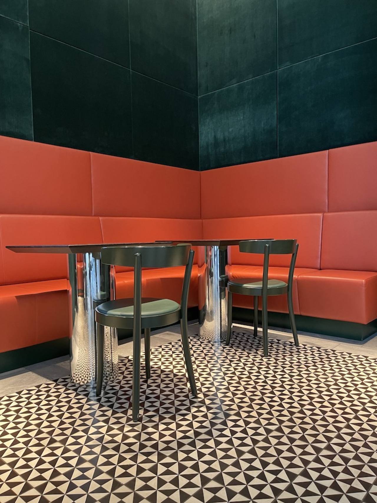 Zementfliese mit kleinen Dreiecken in schwarz weiß mit roter Sitzecke und Bistrostuehlen