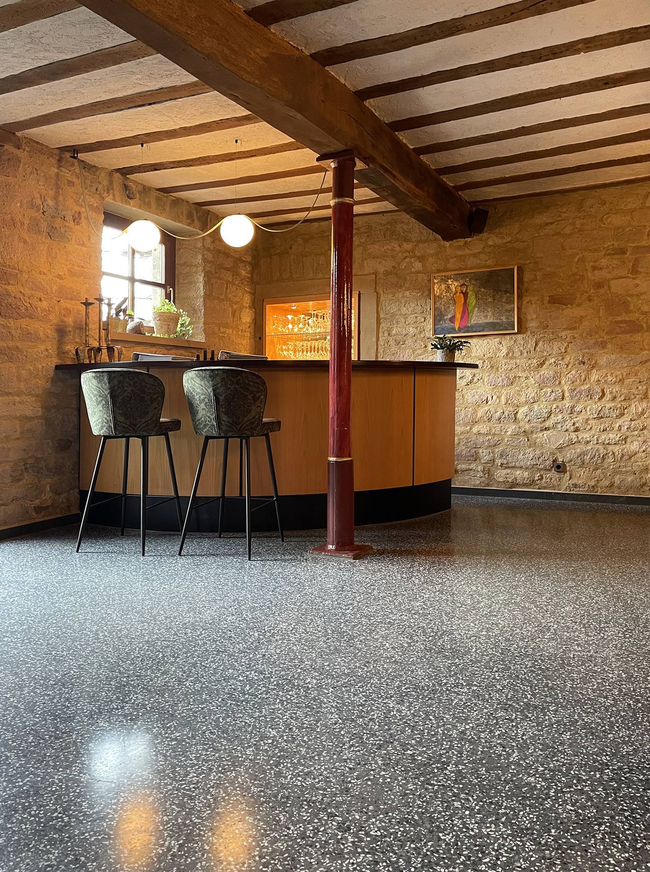 Terrazzo in Raum mit Sandsteinwaenden und Theke mit Barhockern
