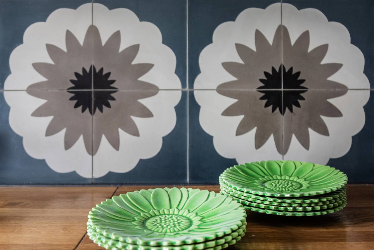 Florale Ornamentfliese in blau und Grautänen an der Wand und grünen Desserttellenn