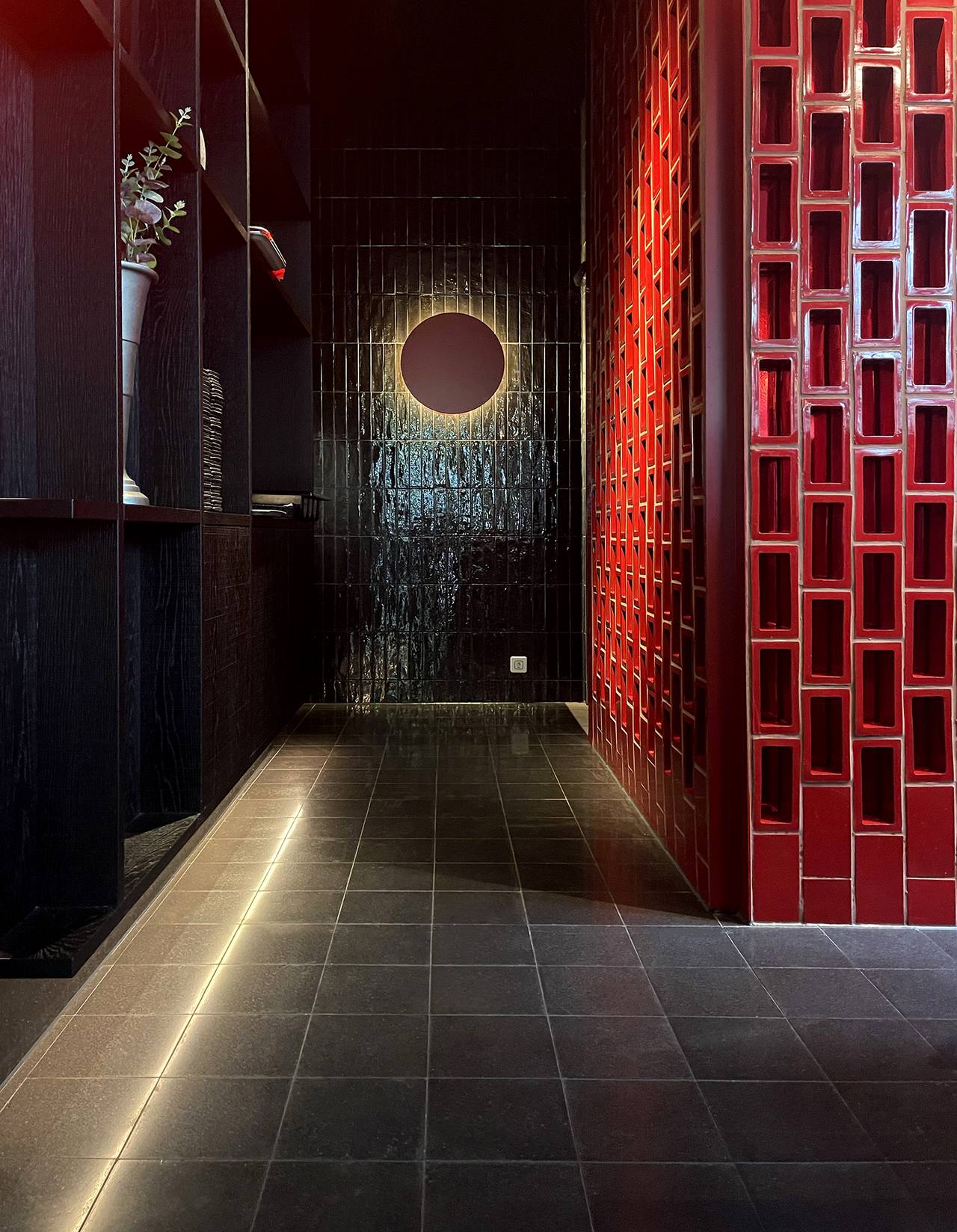 Flur mit schwarzen VIA Terrazzoplatten in Restaurant mit roter Steinwand